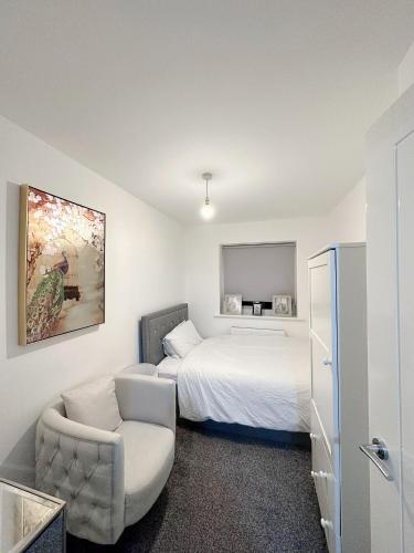 1 dormitorio blanco con 1 cama y 1 silla en Beautiful home en Ince-in-Makerfield