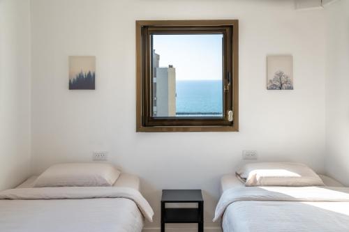 two beds in a room with a window at Roof Top 3 Floors in Netanya