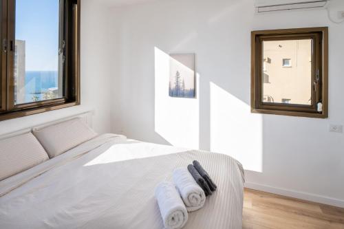 a white bedroom with a bed with towels on it at Roof Top 3 Floors in Netanya