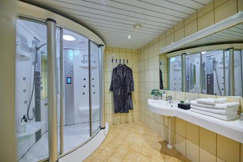 a bathroom with a shower and a sink and mirrors at SPA Hotell Peetrimõisa Villa in Viljandi