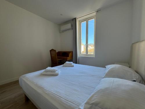 een slaapkamer met een wit bed en 2 handdoeken bij Appartements Centre Cannes in Cannes