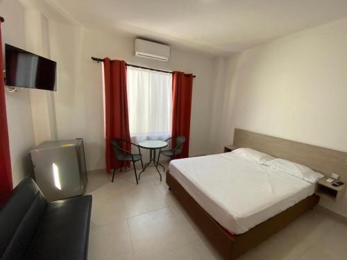 1 dormitorio con cama, mesa y TV en Encanto Apartahotel, en Santa Marta