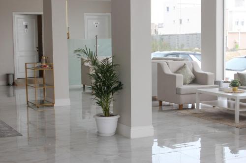 ein Wohnzimmer mit einer Topfpflanze auf dem Boden in der Unterkunft الماطر للشقق الفندقية Almater Hotel Suites in Al Khafji