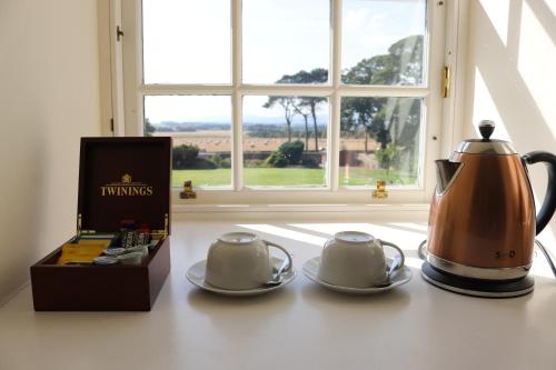 2 théières et une boîte sur un comptoir dans l'établissement Tarrel Farmhouse, à Portmahomack