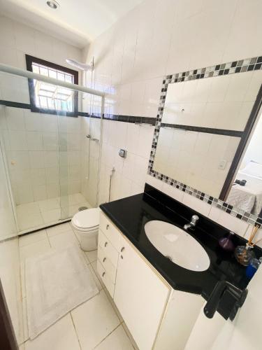 a white bathroom with a sink and a toilet at Nossa Casa em Vilas - 70 m da areia - 6 Suítes in Lauro de Freitas