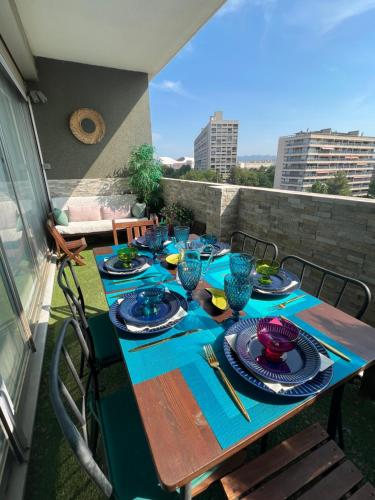 une table avec des assiettes et des verres sur un balcon dans l'établissement 130m2 de standing, 5min plages et stade, Parking gratuit, 5e et dernier étage avec ascenseur, vue montagne, à Marseille