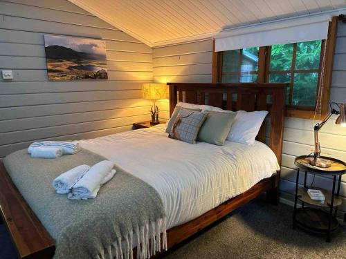 a bedroom with a bed with two towels on it at Panteinion Hall- The Cabin in Fairbourne