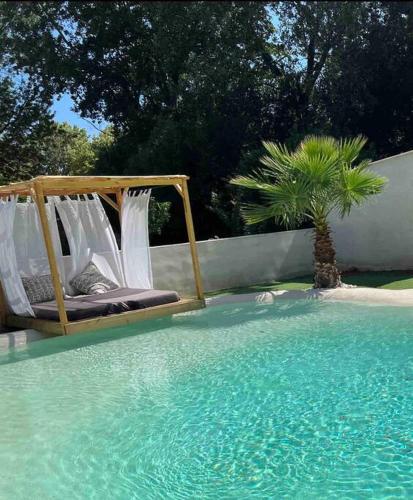 - un lit dans une piscine à côté d'un palmier dans l'établissement La maison des roses 5 Avignon, à Villeneuve-lès-Avignon