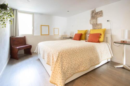 a bedroom with a bed with yellow and orange pillows at Appartement Les Cyprès de l’Île in Avignon