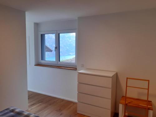 una stanza vuota con cassettiera e finestra di Apartment Panorama am Walensee in Neubau-Villa a Obstalden