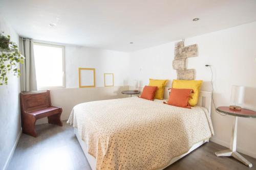a bedroom with a bed with yellow and orange pillows at Appartement Les Cyprès de l’Île in Avignon