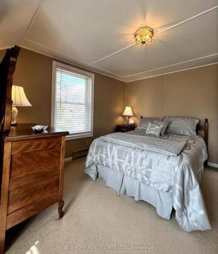 een slaapkamer met een bed, een dressoir en een raam bij Rosedale Cottage@Baksam lake in Fenelon Falls