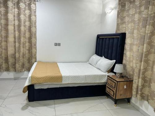 een slaapkamer met een bed en een nachtkastje met een bed sidx sidx bij Cozy home in East Legon Hills in Accra