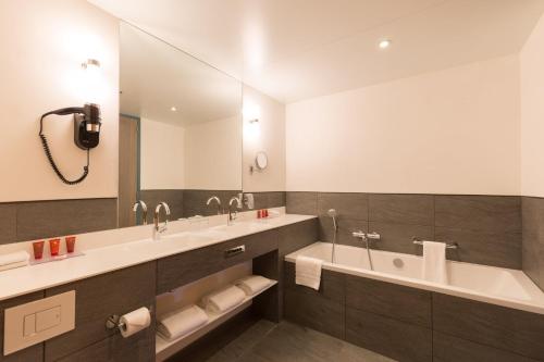 a bathroom with two sinks and a large mirror at Leonardo Hotel Amsterdam Rembrandtpark in Amsterdam