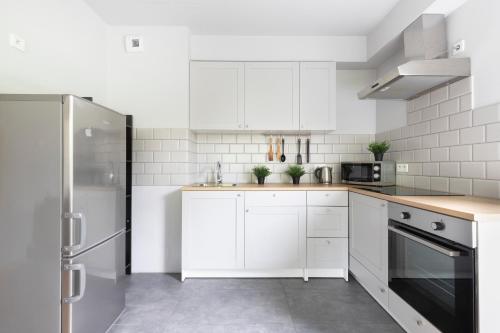 a white kitchen with white cabinets and a refrigerator at Krowodrza Apartment's in Krakow