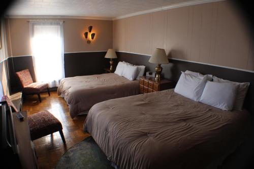 a hotel room with two beds and a window at Historical Hotel - House of Ludington in Escanaba