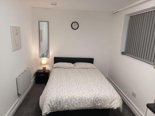 1 dormitorio con 1 cama y reloj en la pared en 188 marsh road en Luton