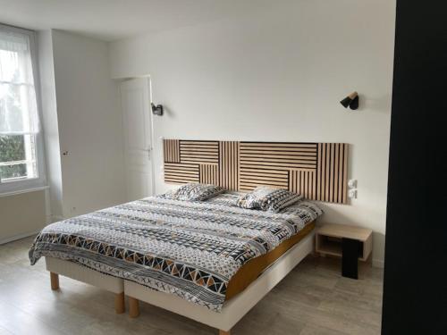 1 dormitorio con 1 cama grande y cabecero de madera en Appart meublé 45m2 calme et lumineux au Continental en Vittel