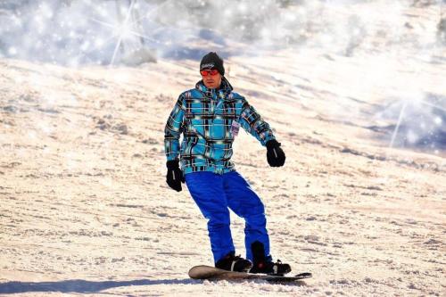 a man riding a snowboard down a snow covered slope at The Mountain Loft in Canmore