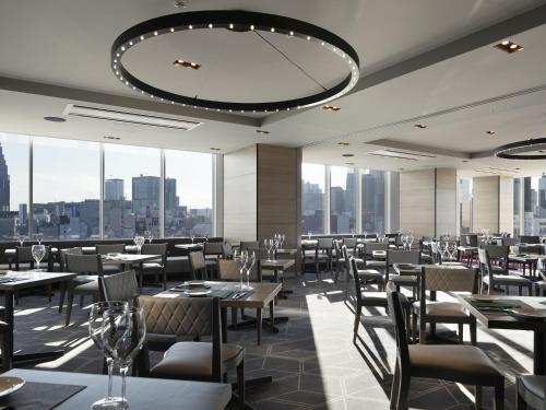 a restaurant with tables and chairs and a large chandelier at Shinjuku Granbell Hotel in Tokyo