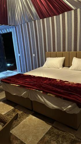 a large bed in a room with a wall at Scarlet Luxury Camp Wadi Rum in Wadi Rum