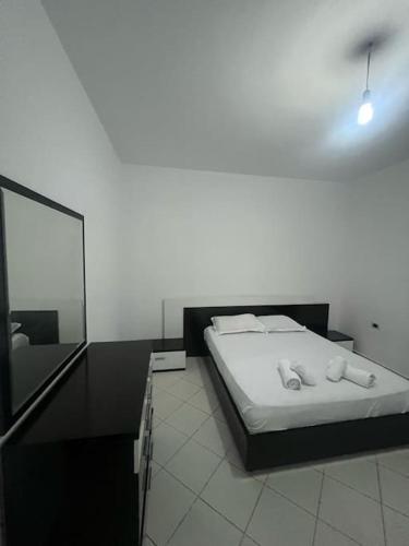 a white bedroom with a bed and a mirror at City view in Elbasan
