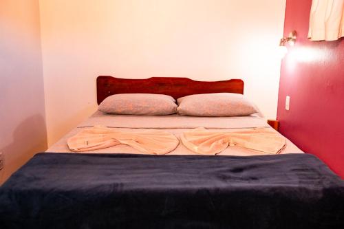 a bed with a blue blanket and two pillows at Pousada Tatu Feliz in Vale do Capao