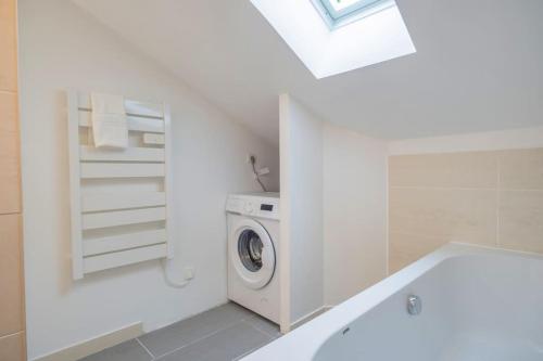 a white bathroom with a washing machine and a sink at Le Boulingrin in Reims