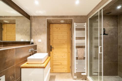 uma casa de banho com um lavatório e um chuveiro em Chalet Abeille in Les Gets Sleeps 12 em Les Gets
