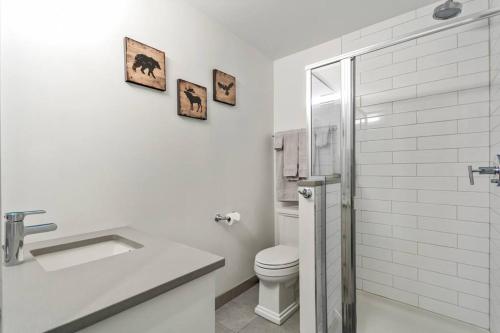een witte badkamer met een toilet en een wastafel bij Mountain Modern Hideaway in Canmore