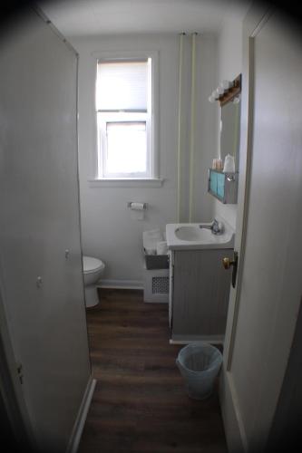 a bathroom with a sink and a toilet and a window at Historical Hotel - House of Ludington in Escanaba