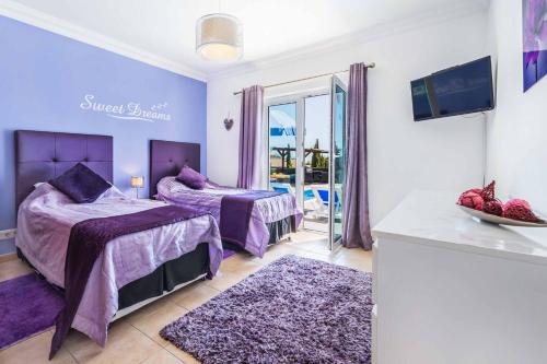 a purple bedroom with two beds and a balcony at Villa Kambu in Quelfes