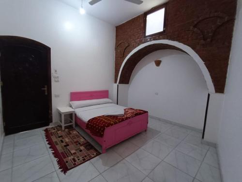 1 dormitorio con cama rosa y puerta negra en Egypt lovers home, en Luxor