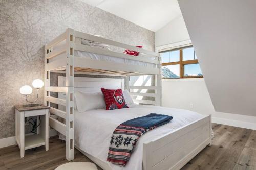 キャンモアにあるThe Grand Escape Downtown Canmoreの白いベッドルーム(二段ベッド、はしご付)