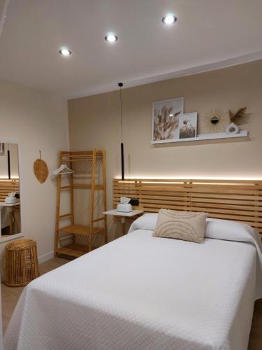 a bedroom with a white bed and a wooden headboard at Pensión Cabezas Oviedo in Oviedo