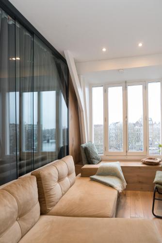 a living room with a couch and large windows at Canal view home in the center in Amsterdam