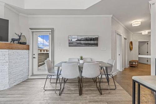 a dining room with a table and white chairs at Mountain Vista Escape Downtown in Canmore