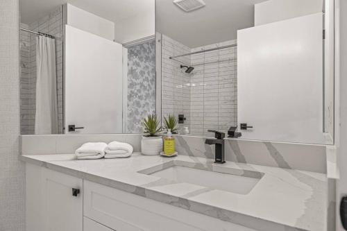 a white bathroom with a sink and a mirror at Mountain Vista Escape Downtown in Canmore