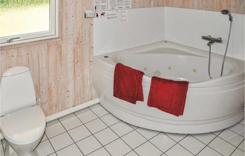 ノーポにあるBeautiful Home In Nordborg With 3 Bedrooms, Sauna And Wifiのバスルーム(バスタブ、赤いタオル2枚付)