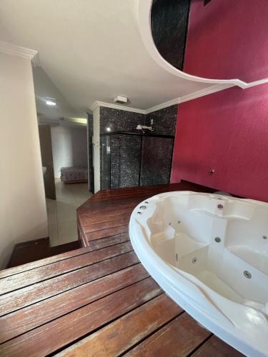 La salle de bains est pourvue d'une baignoire et d'un mur rouge. dans l'établissement Pousada Azul Ms, à Viracopos