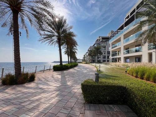a walkway with palm trees next to a building at Luxury the address 3BR in Fujairah