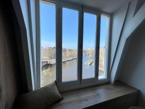 een raam in een kamer met uitzicht op een rivier bij Canal view home in the center in Amsterdam
