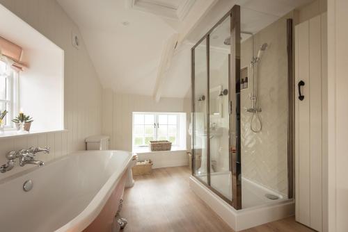 a white bathroom with a tub and a shower at Swallow Cottage in Port Isaac