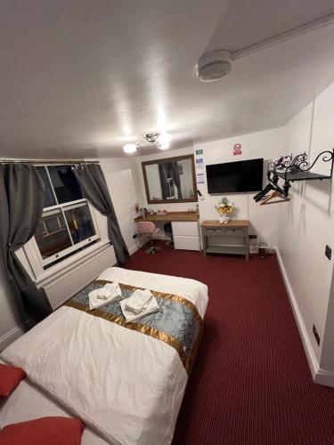 a bedroom with a bed and a desk and a television at HELIN’s Cottage in Whitby