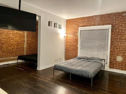 1 dormitorio con cama y pared de ladrillo en Chic Urban Retreat - 5 Mins to LACMA Lights, en Los Ángeles