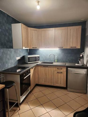 La cuisine est équipée de placards en bois, d'un évier et d'un four micro-ondes. dans l'établissement Chalet Antlana 2 avec cheminée, à Signy-lʼAbbaye