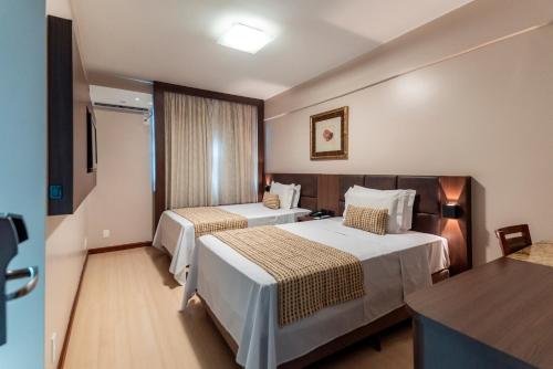 um quarto de hotel com duas camas e uma mesa em Copas Verdes Hotel em Cascavel