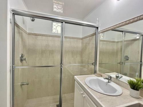 a bathroom with a glass shower and a sink at Crusoe (5 bedrooms, Crownpoint) in Bon Accord