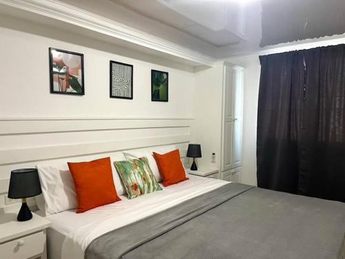 a bedroom with a large bed with orange pillows at Crusoe (5 bedrooms, Crownpoint) in Bon Accord