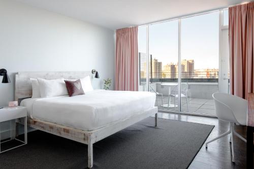 a white bedroom with a bed and a large window at Quirk Hotel Richmond in Richmond